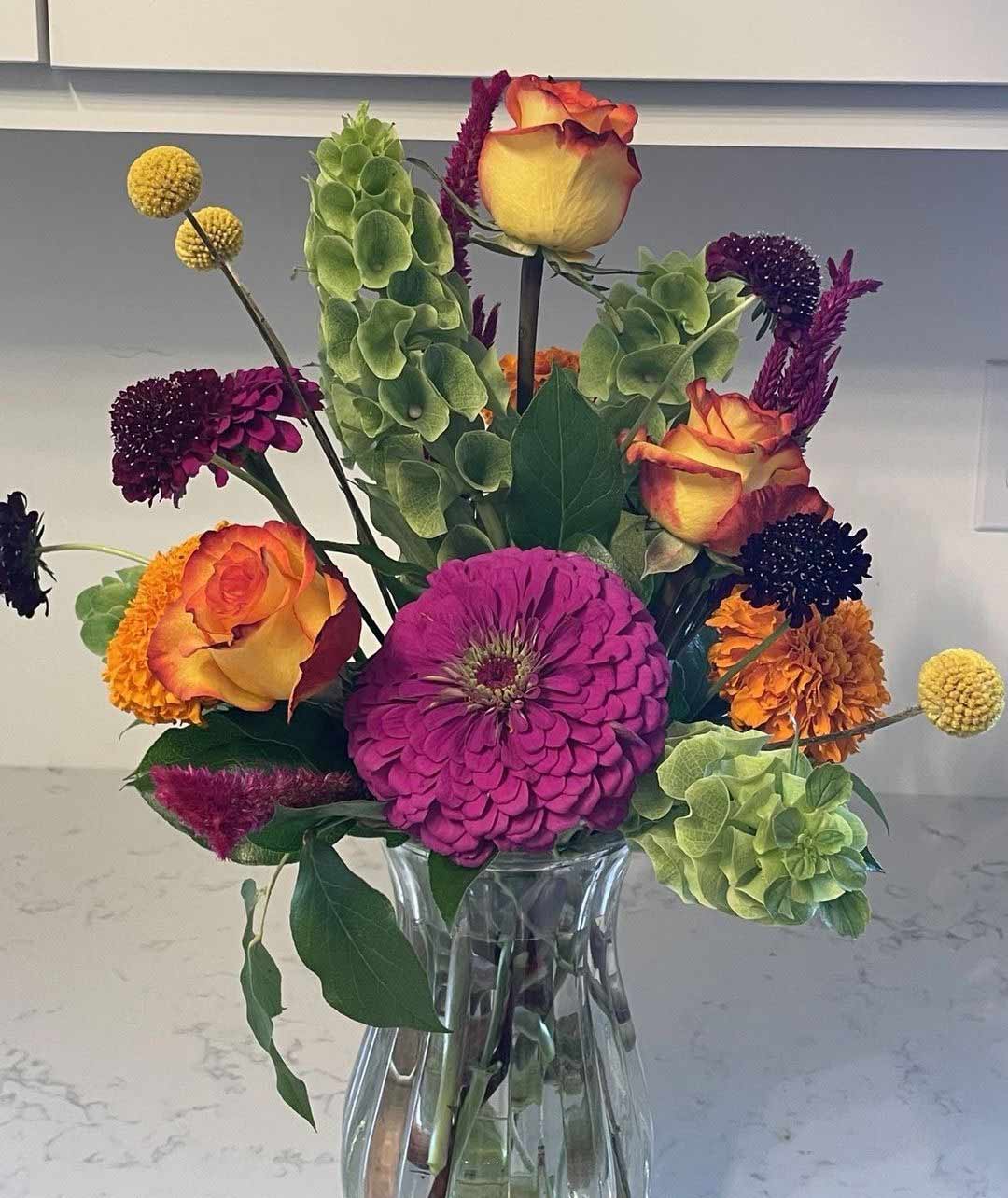 Roses and spring flowers mixed in a clear glass vase